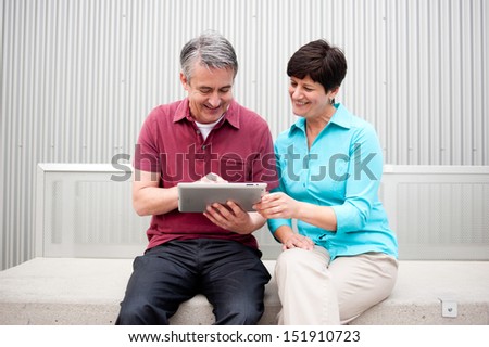 elderly couple sitting, on the tablet computer