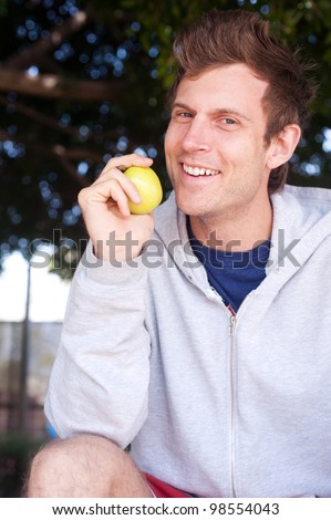 portrait of a healthy young man holding apple outside