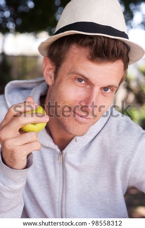 portrait of a young man holding apple outside