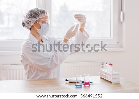 Science, chemistry, technology, biology and people concept - young scientist with test tube making research in clinical laboratory