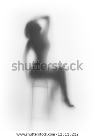 Beautiful woman sits on chair, behind a diffuse glass surface