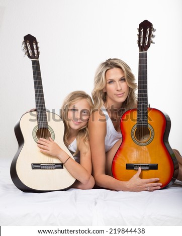 Beautiful blonde mother and her daughter together, with guitars