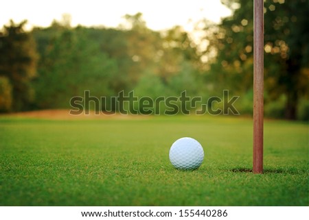 White Golf Ball On Putting Green With Bunker In Background