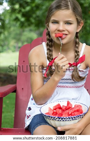Little girl eating a bite of watermelon