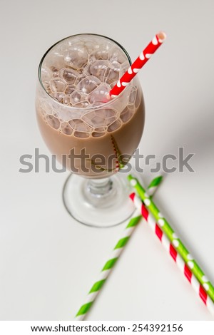 Glass of chocolate milk with bubbles and paper straws