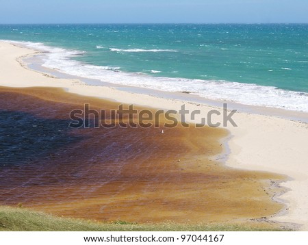 Salt water meets fresh water to form an estuary, split by a beach sand bar.