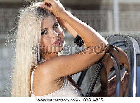 happy young woman with car - sexy rich lady driver with long blond healthy hair at automobile . spring - summer portrait . beautiful slim fashion girl posing near car