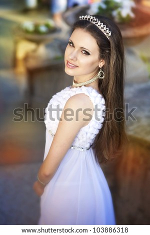 beautiful slim bride in luxury dress in park on sunset in wedding day. young woman in Greek  goddess style with diamond tiara and jewelery outdoor. romantic girl with glossy hair. spring - summer