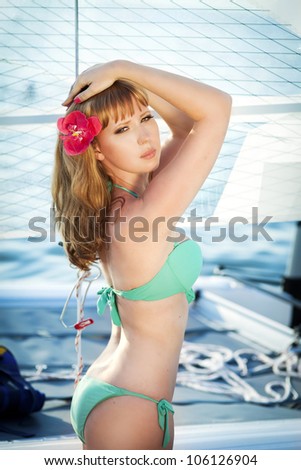 Beautiful slim girl sunbathing rich lady relaxing on the yacht at the seaside. Alluring happy woman in Tropical Resort. Travel and Vacation concept.Ocean Beach. Bikini model posing on deck of ship