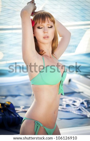 Beautiful slim girl sunbathing rich lady relaxing on the yacht at the seaside. Alluring happy woman in Tropical Resort. Travel and Vacation concept.Ocean Beach. Bikini model posing on deck of ship