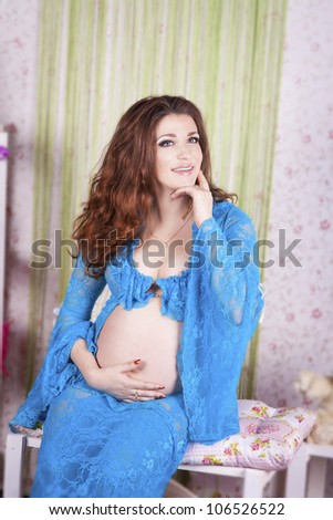 Beautiful pregnant woman at home showing and touching her tummy. Young happy girl in provence interior in bedroom with colored pillows waiting for little baby.Lady dreaming about child.sweet pregnancy