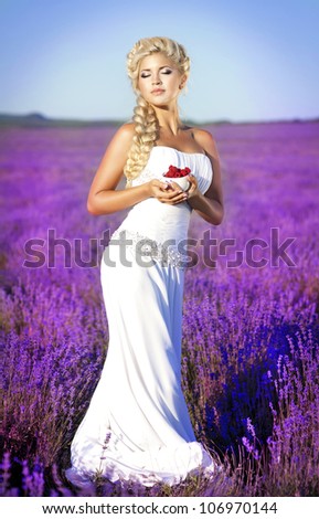 beautiful slim bride in luxurious wedding dress in purple lavender flowers. Fashion romantic happy woman with blond hair. Smiling girl in sunset over summer lavenda field waiting for groom -Provence
