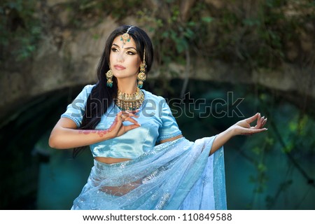 Beautiful young indian woman in traditional clothing with bridal makeup and jewelry. gorgeous brunette bride traditionally dressed Outdoors in India. Girl bollywood  dancer in Sari and henna on hands