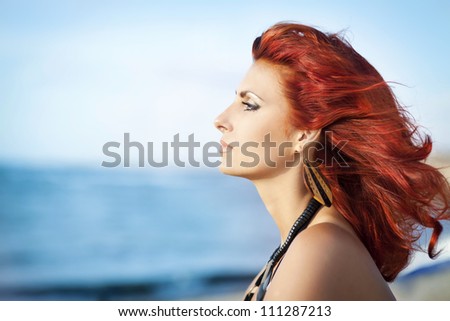 alluring red-hair woman relaxing near sea in swimwear thinking about boyfriend .Beautiful happy girl on beach enjoying summer sun.Romantic lady at vacation holidays at ocean.Sexy pin-up model resting