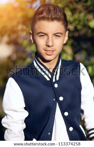 Fashion portrait of handsome teenager posing in casual jacket, young smart European man smiling and trendy dressed. Young guy professional model with modern hairstyle outdoor. happy boy in autumn park