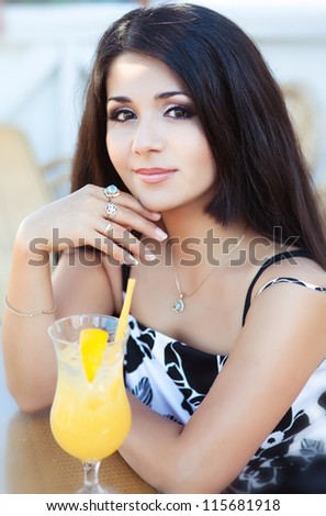 beautiful young happy woman in cafe with fresh orange juice. Stylish sexy lady waiting for someone at restaurant. rich slim brunette girl with extra long hair resting at bar. positively thinking