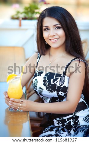 beautiful young happy woman in cafe with fresh orange juice. Stylish sexy lady waiting for someone at restaurant. rich slim brunette girl with extra long hair resting at bar. positively thinking