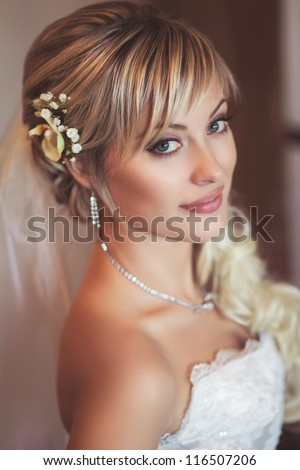 Happy sexy beautiful bride blond girl in white wedding dress with hairstyle and bright makeup waiting for groom. Romantic lady in bridal dress and flowers in hair have final preparation for wedding