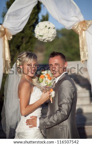 An excited bride and groom laughing and embrace each other on their wedding day, Lovely bride and groom in love smiling and posing in bridal ceremony outdoor at sunset. Happy loving couple.