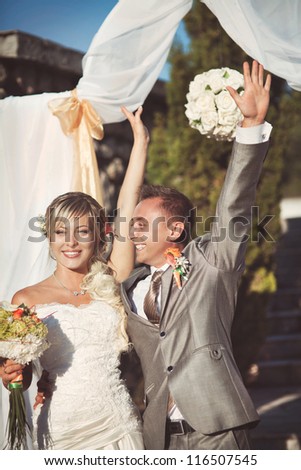 An excited bride and groom laughing and embrace each other on their wedding day, Lovely bride and groom in love smiling and posing in bridal ceremony outdoor at sunset. Happy loving couple.