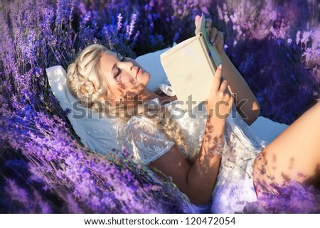 Beautiful provence woman relaxing in lavender field ridding a book and lying in lavanda flowers. Series. alluring girl with purple lavender outdoor. blond lady with hairstyle in blossom field . France