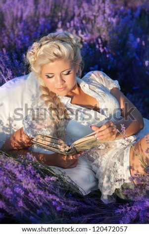 Beautiful provence woman relaxing in lavender field ridding a book and lying in lavanda flowers. Series. alluring girl with purple lavender outdoor. blond lady with hairstyle in blossom field . France