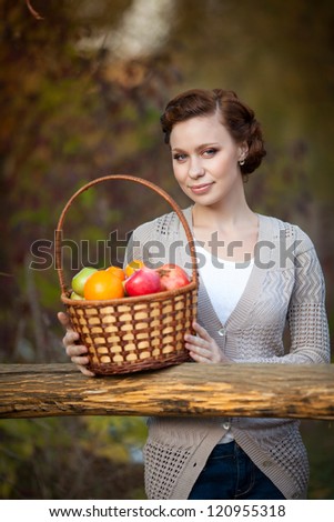 Happy Smiling Young Woman with Organic Apple in basket in the Orchard. Girl with Basket of Apples enjoying the nature. Harvest Concept. Garden. Provence romantic  brunette lady with hairstyle outdoors