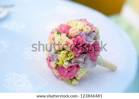 Wedding bouquet of bride - colorful flowers pink, white roses and yellow freesia lying on table at wedding on nature at summer day. Classic and elegant bridal decoration. close up of wedding bouquet