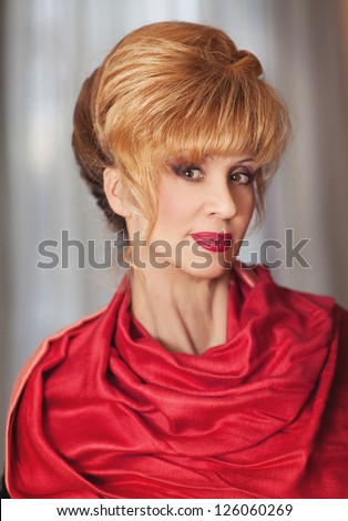 elegant middle aged woman with bright makeup and fashion hairstyle in red scarf posing. Rich happy blond stylish businesswoman relaxing and smiling in evening. cheerful middle aged woman