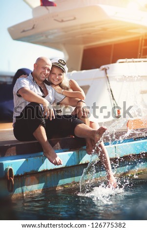 couple in love together near sea and yacht enjoy moment of happiness at honeymoon. Playful family at vacation. handsome man and beautiful woman having fun. Girlfriend and boyfriend on date near ocean.