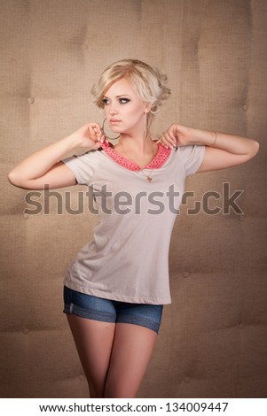 Beautiful blonde woman in jeans shorts casual summer Fashion with hairstyle makeup big earrings. Pinup. Sales and Discounts Concept. Alluring american girl teenager in spring collection. Shopping Mall