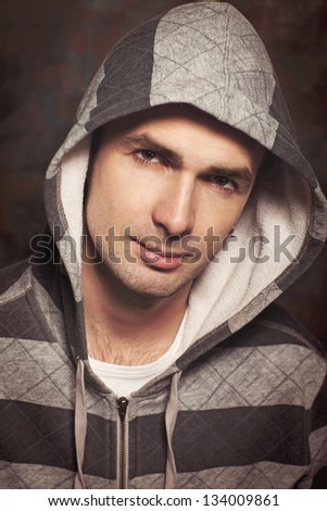 Handsome man portrait on graffiti grunge wall at street in casual sweater. Hip hop dancer angry guy in jacket. Hooligan male mob. Male Fashion. brutal sexy stylish guy model Rapper or rnd singer