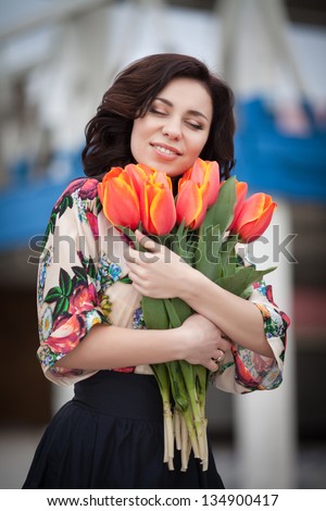 Beautiful woman with flowers bouquet in spring park outdoors. Romantic sexy girl with tulips flowers for anniversary or Valentines. happy smiling woman with bouquet. brunette woman on dating summer