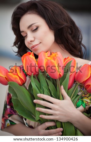 Beautiful woman with flowers bouquet in spring park outdoors. Romantic sexy girl with tulips flowers for anniversary or Valentines. happy smiling woman with bouquet. brunette woman on dating summer