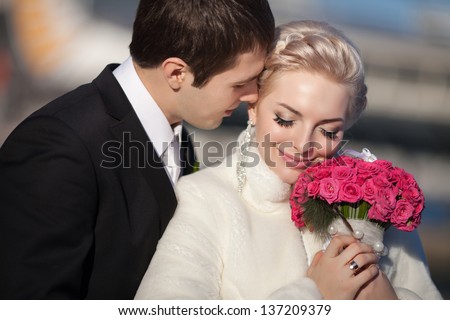 Wedding bride and groom kissing loving couple with roses bouquet flowers at winter bridal day Enjoy moment of happiness and having fun. playful newlywed family woman and man in love. gorgeous bride