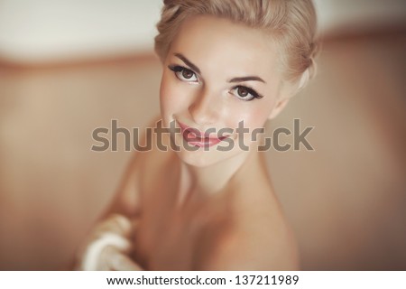 Gorgeous bride blonde in wedding dress in luxury interior with diamond jewelry posing at home and waiting for groom. Romantic rich happy girl in bridal dress smiling have final preparation for wedding