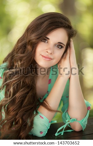 Beautiful happy woman girl smiling outdoors in green summer nature. Pretty woman with natural makeup curly hairstyle in country village in park. Attractive beauty Healthy girl. healthy life concept