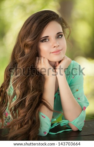 Beautiful happy woman girl smiling outdoors in green summer nature. Pretty woman with natural makeup curly hairstyle in country village in park. Attractive beauty Healthy girl. healthy life concept