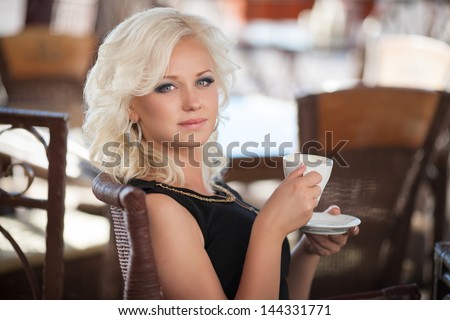 Alluring woman drinking coffee in cafe restaurant in morning sexy blonde girl with cup of latte cappuccino happy smiling. Beautiful retro woman in cafe with mug of hot chocolate. Glamour vintage woman