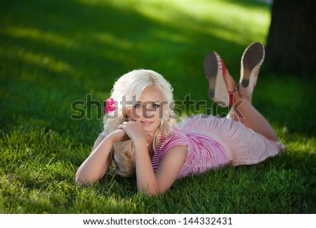 Alluring Woman relaxing outdoors looking happy and smiling sexy blonde girl in summer park. Glamour trendy woman on green grass, Happy woman at vacation. beautiful woman on green grass in summer