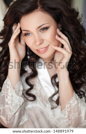 Gorgeous bride woman with wedding makeup and hairstyle, beautiful bride in wedding morning. Rich bride in diamond jewelry at home waiting for groom. Newlywed woman have final preparation for wedding
