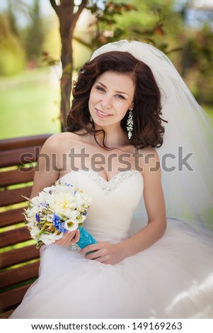 Beautiful bride in wedding dress and bridal bouquet, happy newlywed woman with wedding flowers, woman with wedding makeup and hairstyle. gorgeous young bride outdoors. Bride waiting for groom. bride