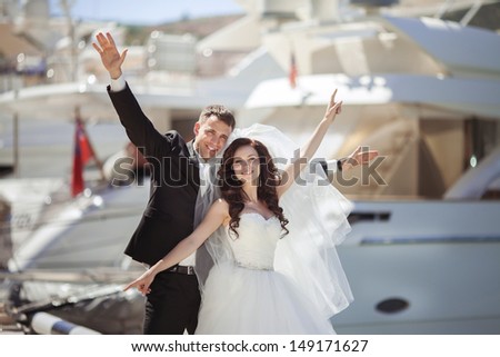 Beautiful bride and groom wedding couple dancing near sea yacht. Happy newlywed couple at wedding. Cheerful married couple standing on the beach. Monaco wedding. Cote de azure Gorgeous wedding outdoor