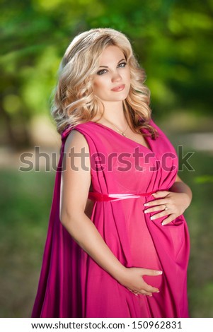 Attractive pregnant woman at nature, pregnancy girl. beautiful pregnant girl outdoors. Happy pregnancy. Happy pregnant woman relaxing in park. Pregnant woman with wreath. Pregnant girl with flowers.