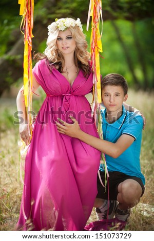 Happy family. Pregnant woman and her teenager son outdoors. Mother and son relaxing on nature. Young woman with teen son in autumn park. Happy pregnancy. Pregnant mother and son. Family vacation.