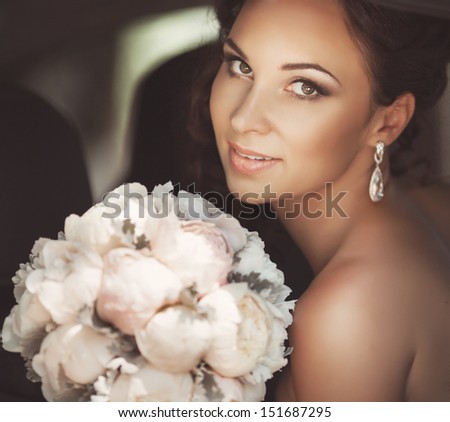 Beautiful bride at wedding car. Happy newlywed woman smiling. Wedding day moment. Bride with wedding flowers bouquet. Woman in wedding dress with bouquet. Wedding makeup. Gorgeous bride. Series.