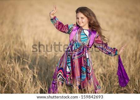 Adorable little girl dancing outdoors in traditional turkish costume. Happy baby girl bellydancer at Turkey. Smiling dancing kid outdoor. Girl in wheat field autumn. Cute little kid at countryside