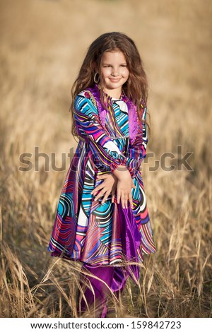 Adorable little girl dancing outdoors in traditional turkish costume. Happy baby girl bellydancer at Turkey. Smiling dancing kid outdoor. Girl in wheat field autumn. Cute little kid at countryside