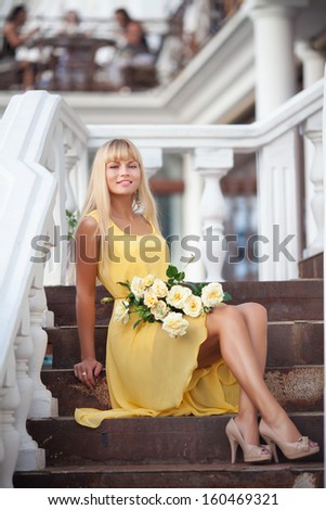 Elegant beauty woman with flowers smiling outdoors. Happy teenager girl walking street. Natural beauty woman. Fashion summer woman in yellow dress. Woman vacation.