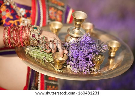 Indian girl with traditional plate of religious offerings and lavender flowers for tea ceremony. Bangles on Beautiful Jeweled Indian Dancer. Indian woman dancing in traditional dress. Indian jewelry